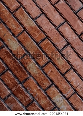 Close-up view of dark reddish-brown bricks laid diagonally, emphasizing the rough, inconsistent surface texture and dark mortar lines. Ideal as a grunge or urban background element.