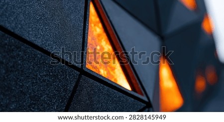Close-up view of a dark, textured surface with geometric patterns and glowing orange triangular elements, creating a modern and abstract aesthetic.