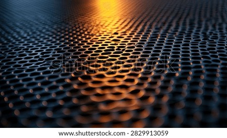 Close-up view of a dark, textured surface with a repeating hexagonal pattern, illuminated by a warm orange light reflecting on its surface.