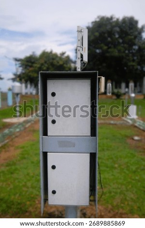 A close-up view of a data logger unit from an automatic weather station (AWS) installed in a meteorological observation field. The device records data from many kinds of weather sensors.