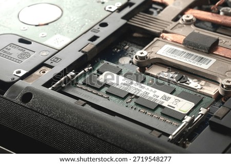 Close-up view of a DDR3 RAM module installed in a laptop motherboard slot next to a hard disk drive. Represents hardware expansion, dual-channel configuration, and system maintenance.