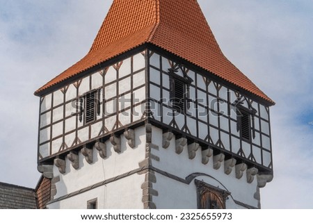 Closeup view of decorative gate tower of Blatna water castle with red roof, consoles holding the top