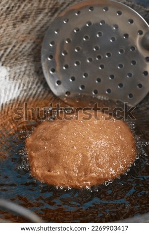 close-up view of deep frying process of sri lankan sweet called kevum or kavum, traditional dessert made from rice flour and palm sugar or kithul sugar, selective focus