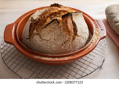 Closeup view of delicious freshly baked sourdough wholewheat bread cooling in a clay pot.