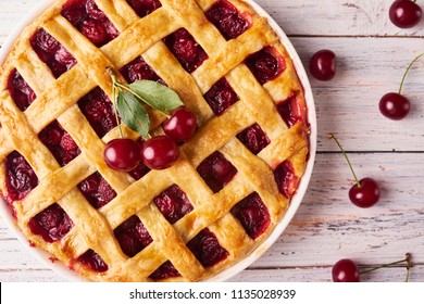 Close-up view of Delicious Homemade Cherry Pie with a Flaky Crust on rustic wooden white background. Top View