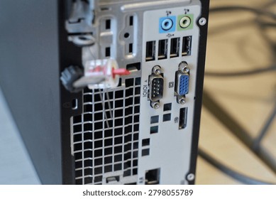 Close-up view of a desktop computer back panel with multiple ports and connectors including USB, VGA, serial and audio jacks