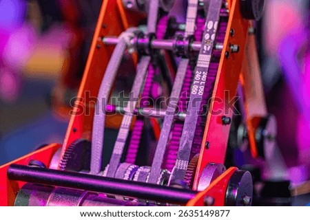 Close-up view of a detailed, layered mechanical robot arm with metallic gears and linkages, predominantly gray and orange in color Realistic style focusing on technical detail perspective suggests
