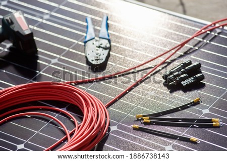 Close-up view of different details and instruments for mounting and connecting solar photovoltaic system. Objects laying on blue solar panel. Alternative energy resources renewable ecologycal concept.