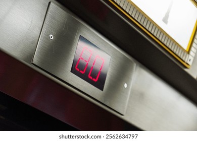 A close-up view of a digital elevator display showing the floor number 80 in bright red. This modern, metallic panel adds a sleek touch to the elevator's interior.