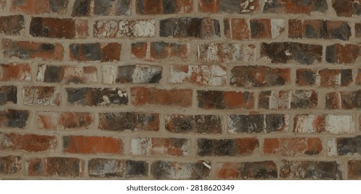 A close-up view of a distressed, multi-colored brick wall featuring varied shades of red, brown, and dark tones.