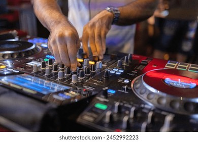 Close-up view of a DJ's hands expertly manipulating a music mixer's controls, focusing on the illuminated buttons and sliders during a live set. - Powered by Shutterstock