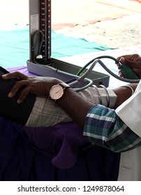 Closeup View Of Doctor Checking Blood Pressure Or BP Of A Patient Using An Equipment In Medical Camp          