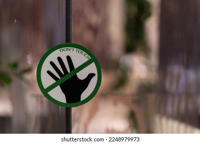 Closeup view of the "Don't touch" sign on the glass. - Shutterstock ID 2248979973