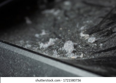 A Closeup View Of Dust Bunnies On A Black Plastic Surface.