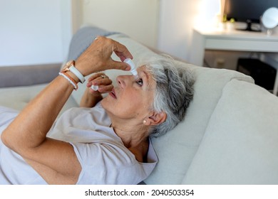 Closeup View At An Elderly Women Using A Bottle Of Eyedrops Due To Ophthalmic Problems. An Older Woman Using Eye Drops For Better Vision. A Senior Woman Is Dropping Liquid In Her Eye With Eye-dropper.