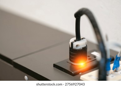 A close-up view of an electrical plug connected to a socket, showcasing an illuminated switch. This image highlights modern electrical technology and its common use in various settings.