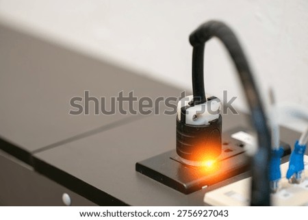 A close-up view of an electrical plug connected to a socket, showcasing an illuminated switch. This image highlights modern electrical technology and its common use in various settings.