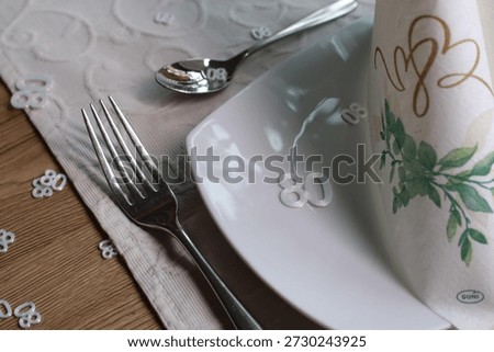 Close-up view of an elegant table setting featuring a white number eighty placed on a dinner plate beside polished cutlery and a decorative table runner. The image represents an eightieth birthday celebration or milestone anniversary. Soft lighting and shallow depth of field create a refined and calm atmosphere, suitable for family celebrations, hospitality, dining events, and special occasions.