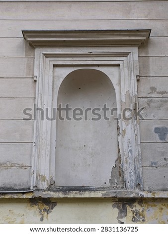 A close-up view of an empty classical architectural niche on the weathered, peeling facade of a historic mansion.