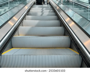 Close-up view of an empty escalator in a modern building with glass railings at Cincinnati-Northern Kentucky International Airport with shadows - Powered by Shutterstock