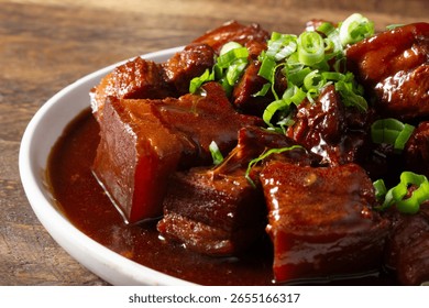 A closeup view of an entree of braised pork belly in brown sauce.