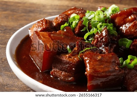 A closeup view of an entree of braised pork belly in brown sauce.