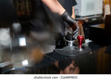 Close-up view of female barista hand holding portafilter and coffee tamper making an espresso coffee by press freshly ground morning coffee on a coffeeshop tablet. Cafe coffee brewing Service Concept. - Powered by Shutterstock