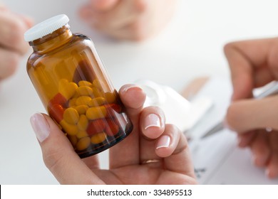 Close-up view of female doctor's hand holding bottle with pills and writing prescription. Healthcare, medical and pharmacy concept. - Powered by Shutterstock