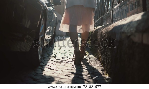 Close-up view\
of female feet walking through the urban street. Female in shoes\
and skirt going in the city\
centre.