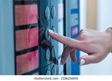 Close-up view of female hand with white nails pressing red button of blue vending coffee machine. Selective focus. Small business. Food and drink theme.