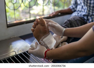 A Close-up View Of A Female Nurse Wrapping A Cloth Over An Elderly Foot Wound Inside A Health Center In Rural Thailand.