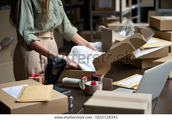 Closeup view of female online store small\
business owner seller entrepreneur packing package post shipping\
box preparing delivery parcel on table. Ecommerce dropshipping\
shipment service\
concept.