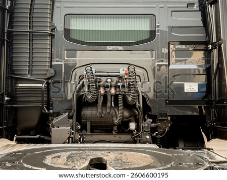 Close-up view of a fifth wheel coupling system and electric cables on a lorry unit. The secure connection between the truck and trailer ensures safe and efficient transportation