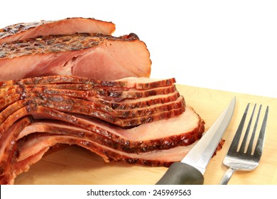 Close-up view Finally backed pre cooked smoked Spiral-cut of Pork Ham over wooden cutting board ready to arrange American South Traditional New Years Day meal over white background 
