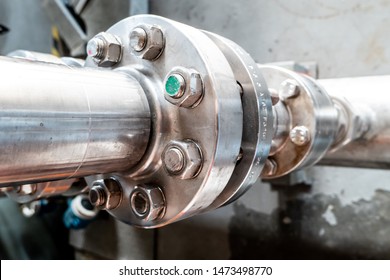 Close-up View Of The Flange With Bolts Of A Heavy Metal Joint On A Pipe That Transports Liquid To An Industrial Plant