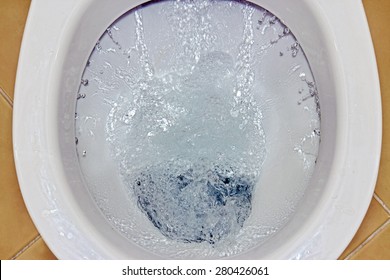 Closeup view of a flushing white toilet. The water swirls in the toilet bowl.  - Shutterstock ID 280426061