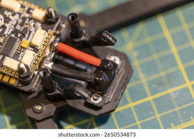A closeup view of an FPV drone circuit board lying on a precision cutting mat background. Concept of modern electronics and DIY drone assembly.