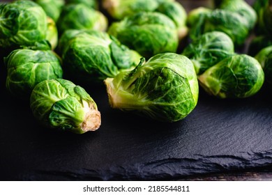 Closeup View Of Fresh Brussels Sprouts Scattered On A Dark Stone Background: Side View Of Brussels Sprouts On A Rustic Slate Rock Background