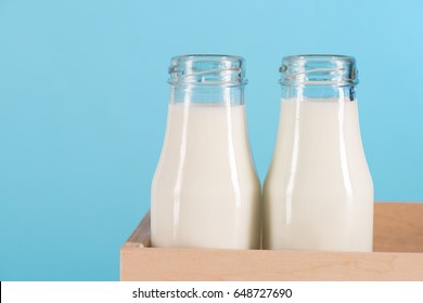 Close-up view of fresh organic milk in glass bottles in box isolated on blue