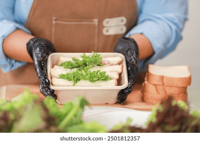 close-up view of a freshly prepared sandwich placed on a wooden cutting board. The sandwich, filled with lettuce, ham, and cheese, is cut in half, showcasing the layers of fresh ingredients - Powered by Shutterstock