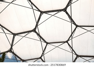 A close-up view of a geodesic dome structure, showcasing hexagonal panels and metal framework. At Eden Project in Cornwall - Powered by Shutterstock