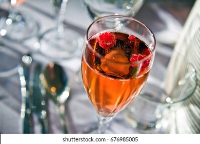 Closeup view of glass of delicious currant pink champagne with raspberry in it. 