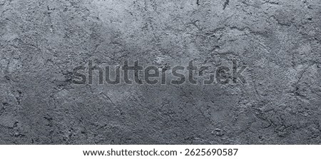 Close-up view of a gray cement wall with a rough texture, natural marks, and subtle imperfections on the solid surface.