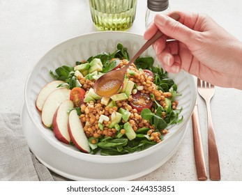 Close-up view: hand holding spoon with vinaigrette dressing salad of greens, lentils, avocado and apple. Healthy food. - Powered by Shutterstock