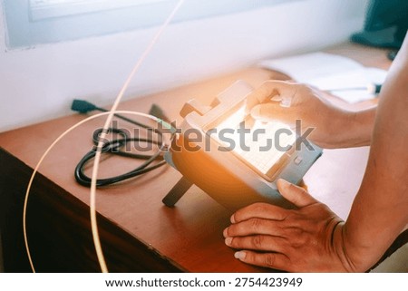 A close-up view of a hand using a modern monitoring device with a touchscreen in a workspace, showcasing technology and interaction in data tracking.