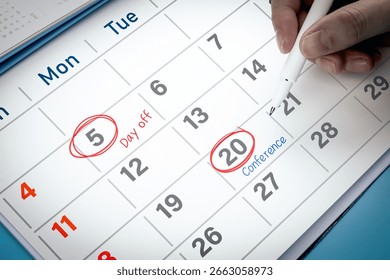 Close-up view of hand using pen to draw red circle on calendar with write word Conference. Concept of appointment reminder, and mission schedule.
