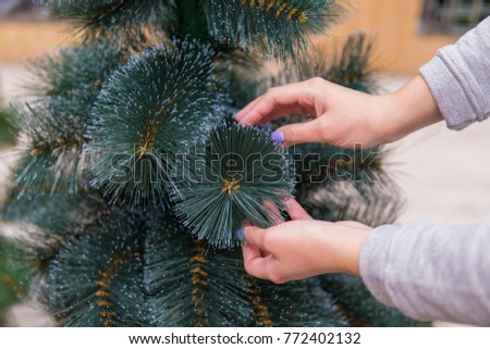 closeup view of hands choosing faux Christmas tree on Christmas Eve. Save nature concept