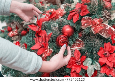 Closeup view of hands decorating Christmas tree with decoration balls. Beautiful holiday decoration.