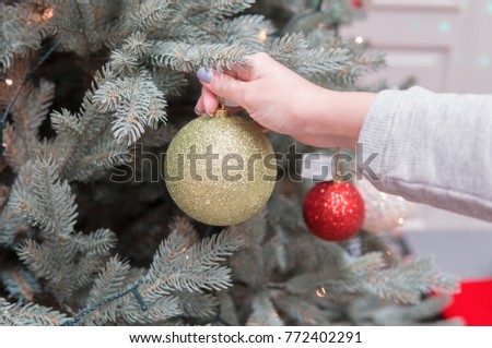 Closeup view of hands decorating Christmas tree with decoration balls. difficult decision.