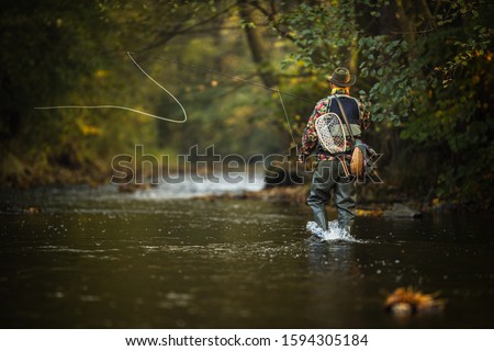 Close-up view of the hands of a fly fisherman holding a lovely trout while  fly fishing on a splendid mountain river